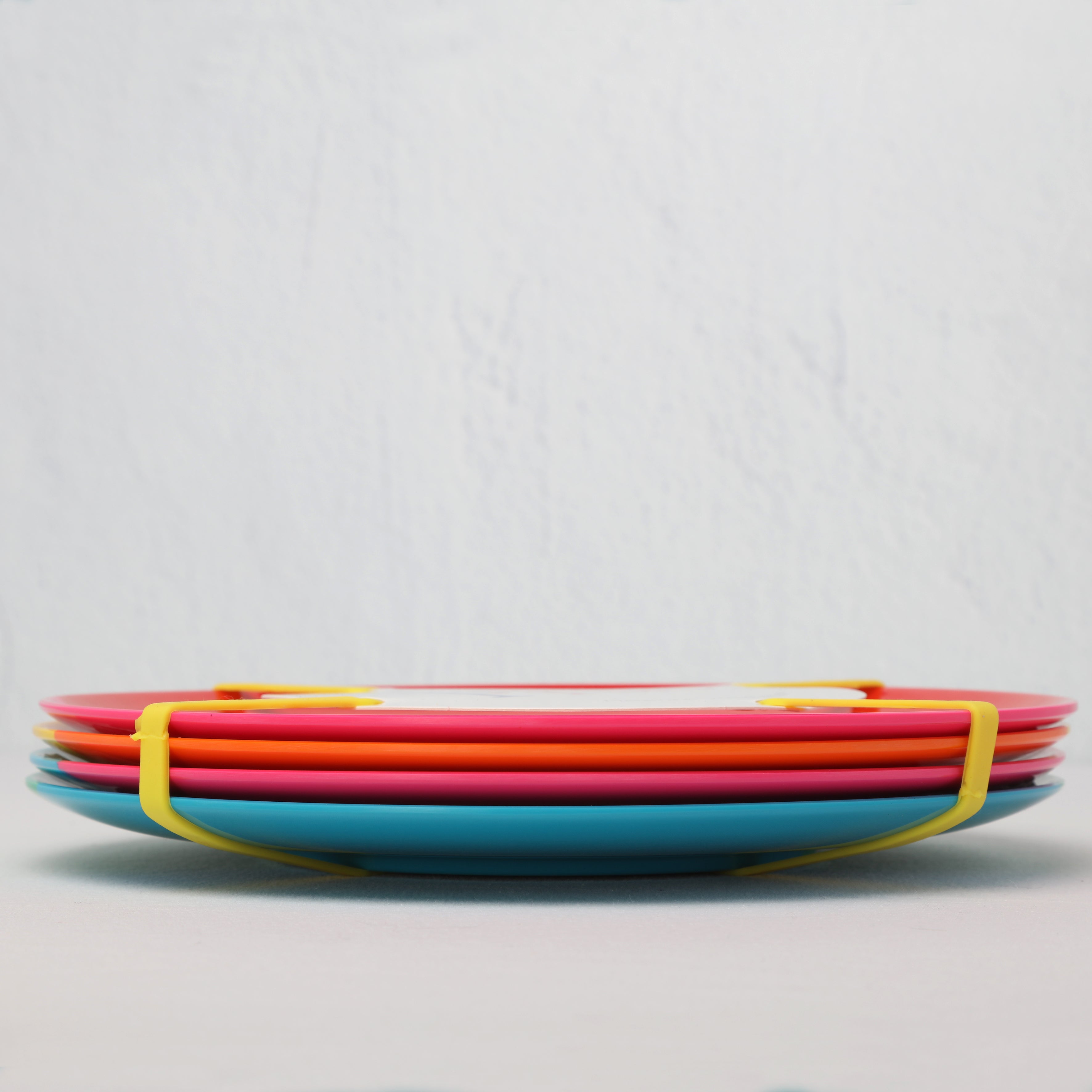 Stack of colorful melamine plates on a light gray background side view