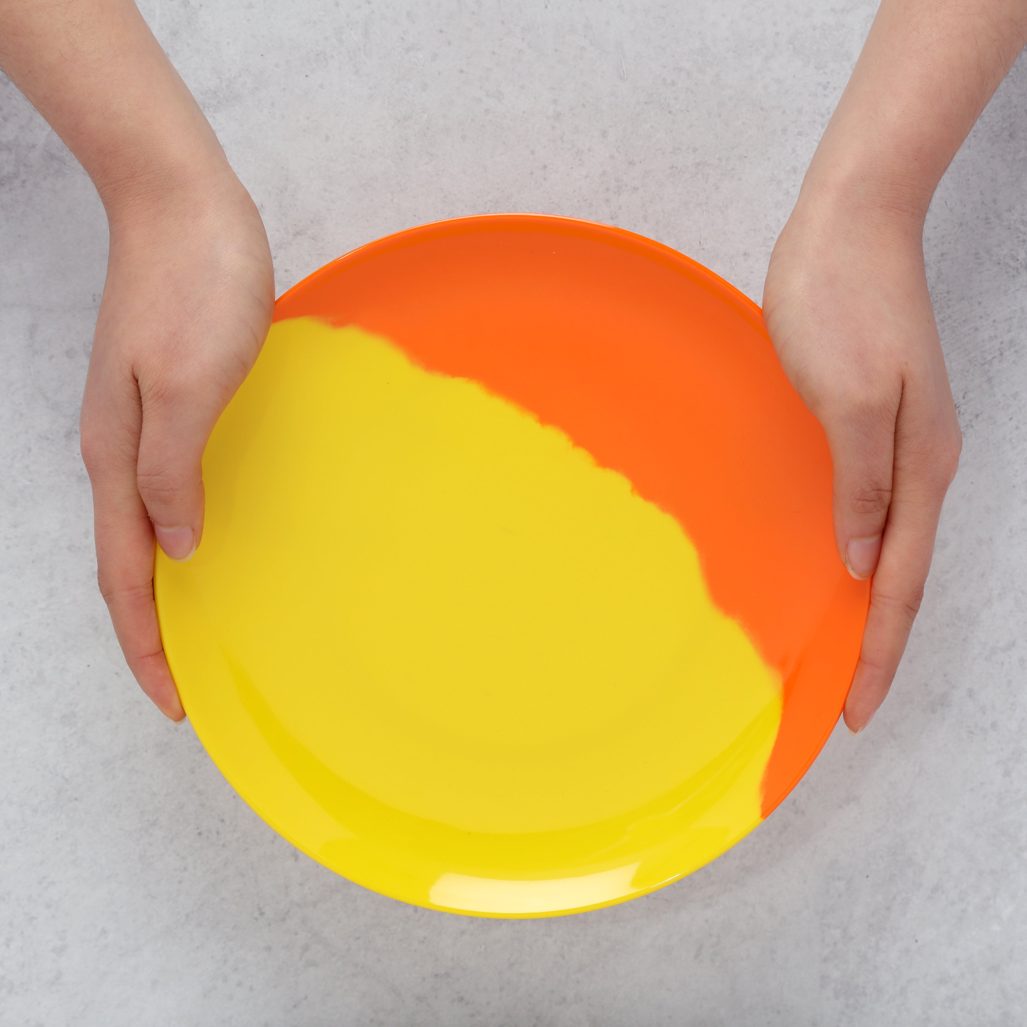 Colorful melamine plate held by hands on a light gray background