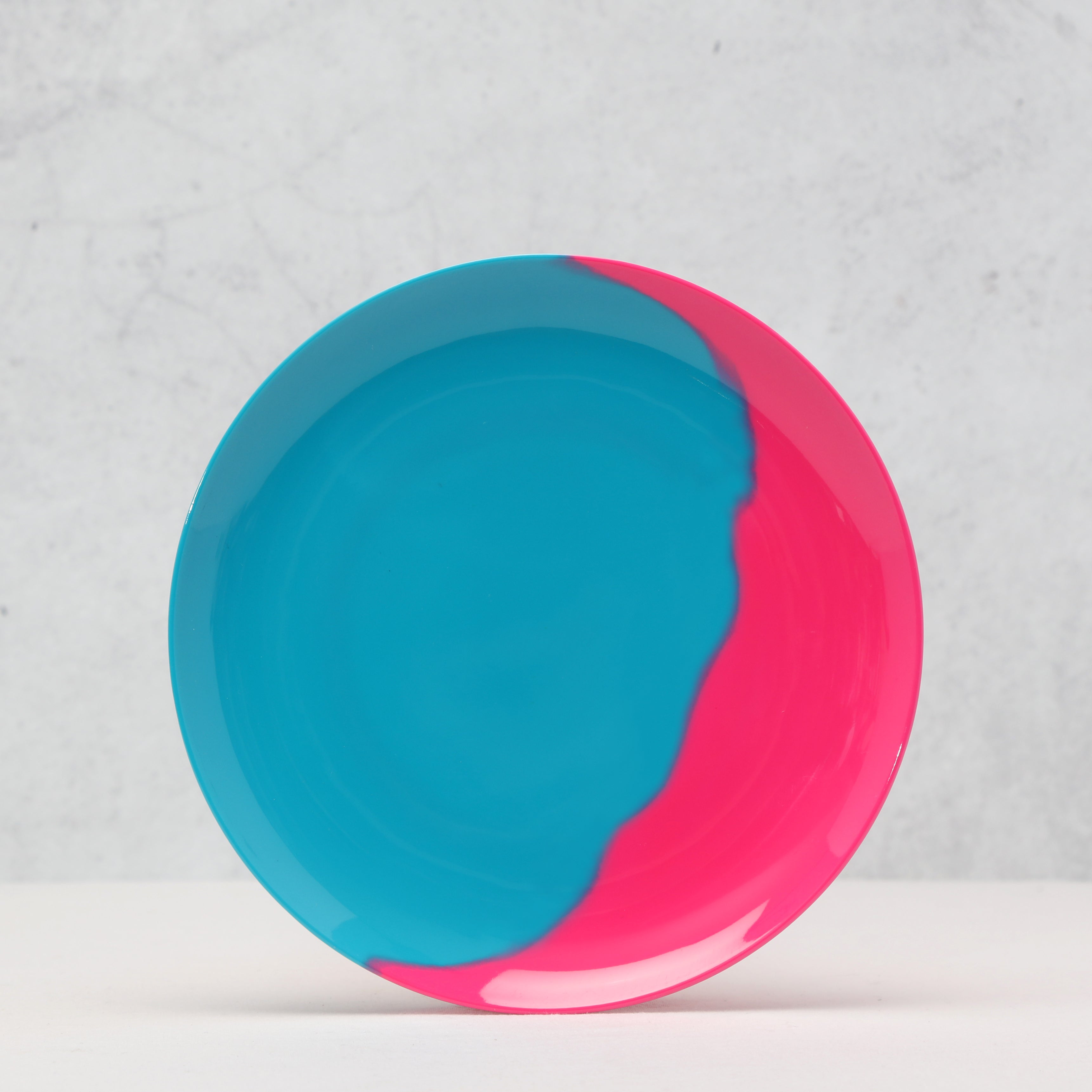Pink and blue melamine side plate on a light gray background.