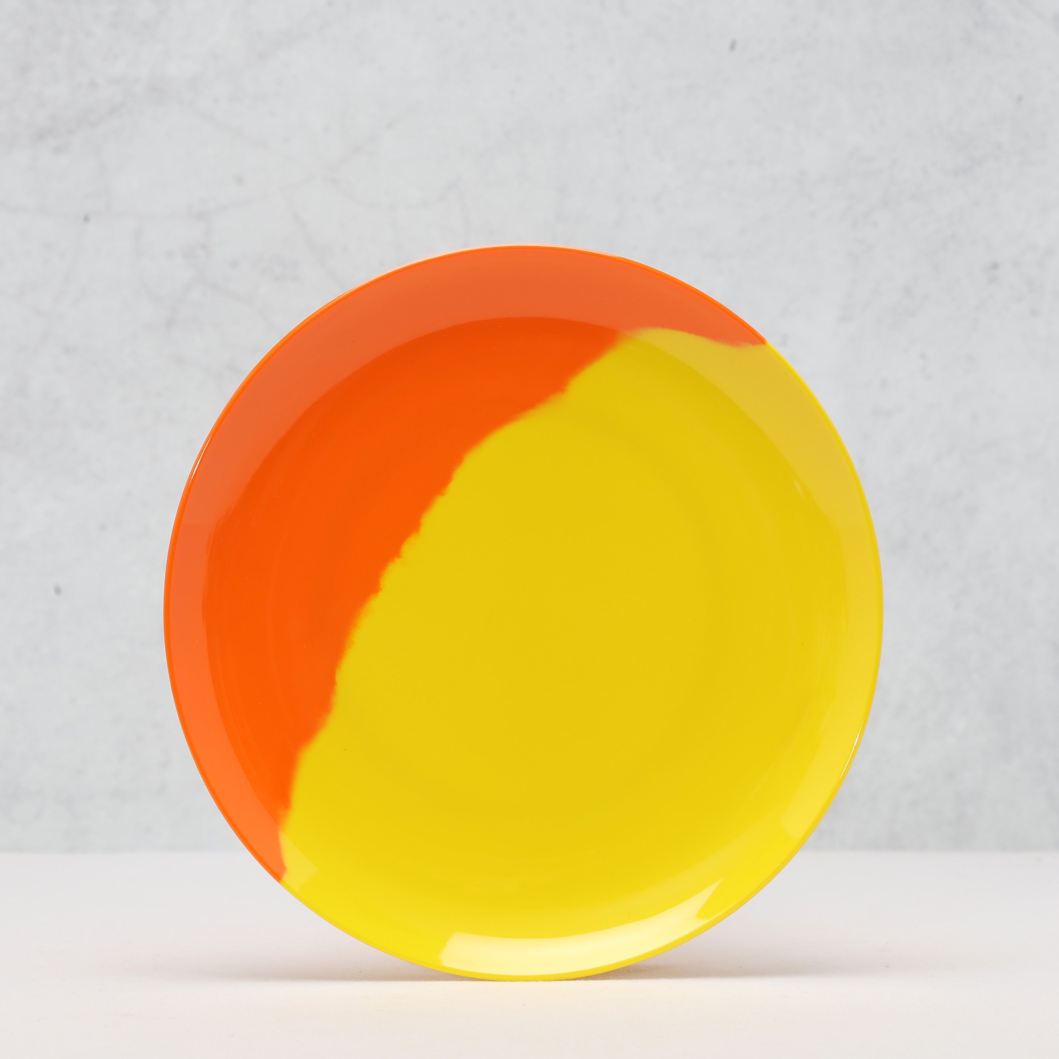 Round plate with orange and yellow design on a light gray background