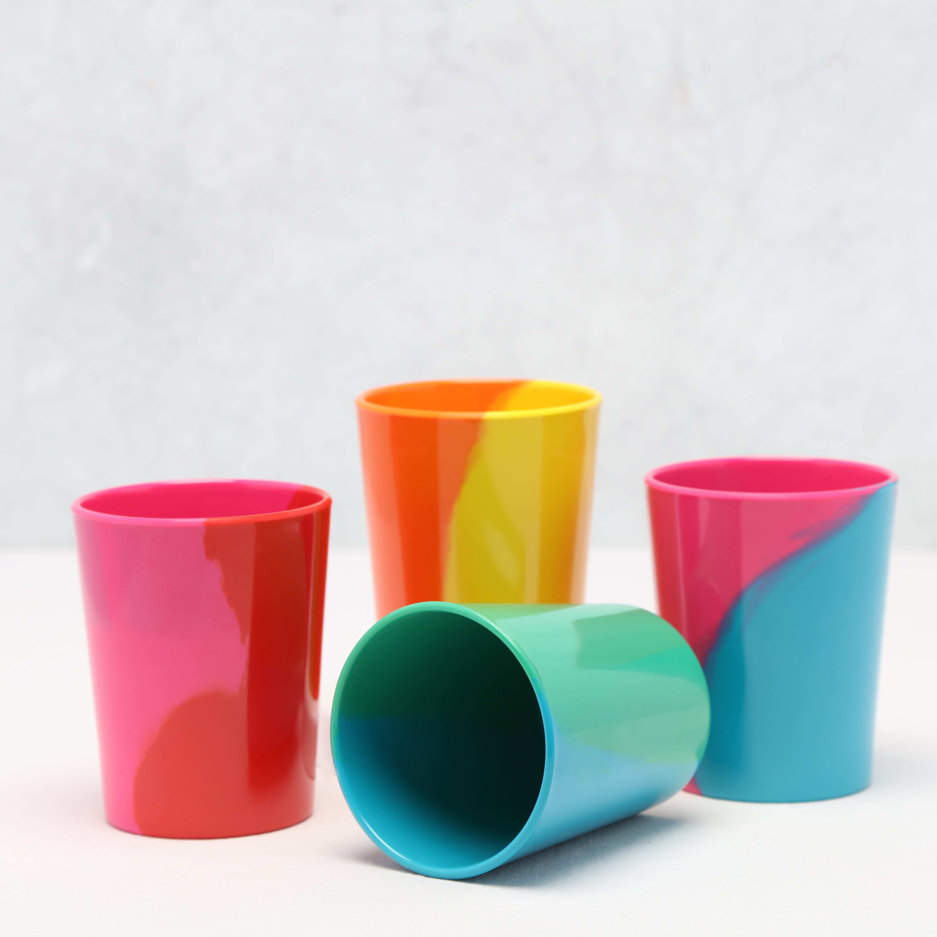 Four colorful tumblers with a two-tone design on a white background