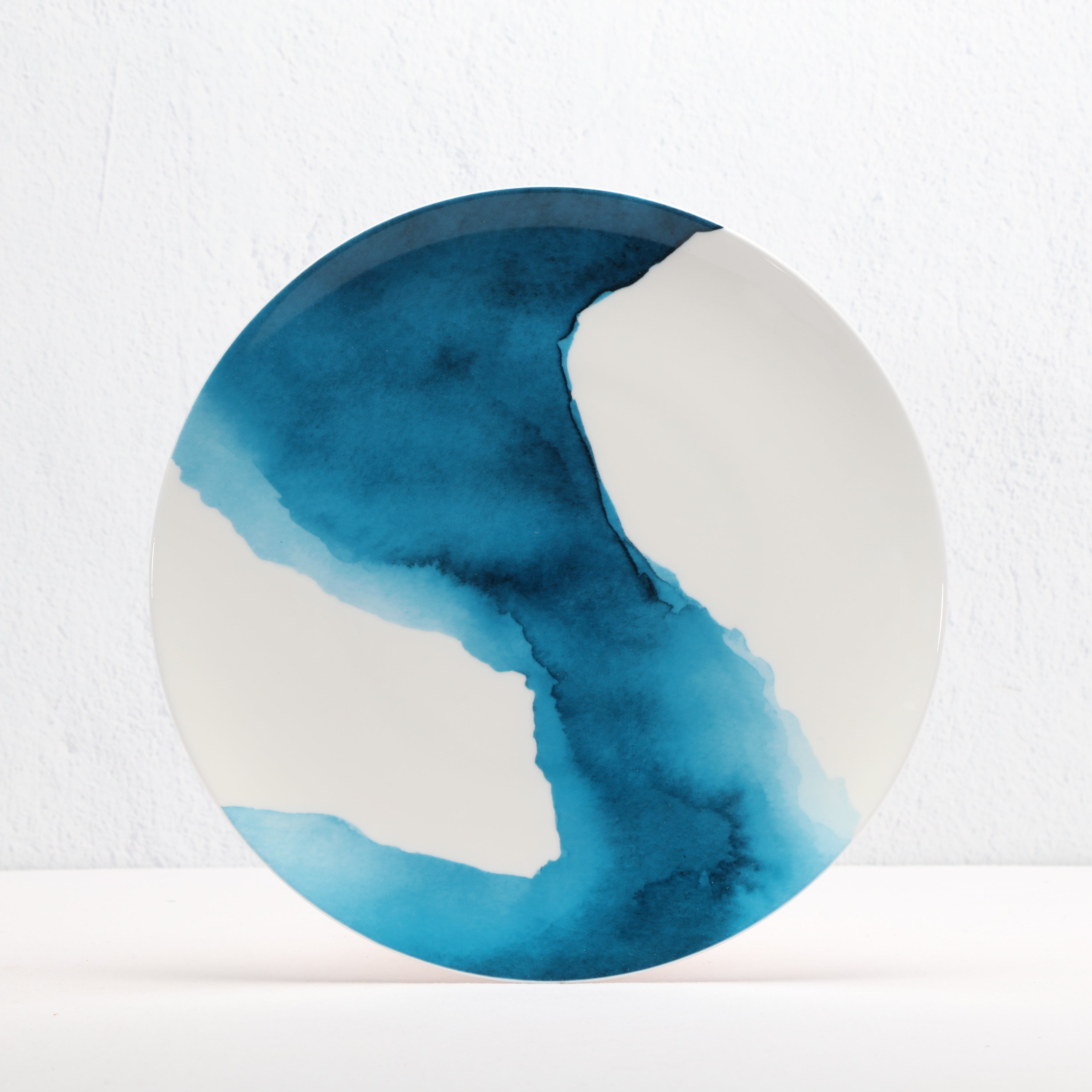 Round bone china ceramic plate with blue watercolour design on a white background