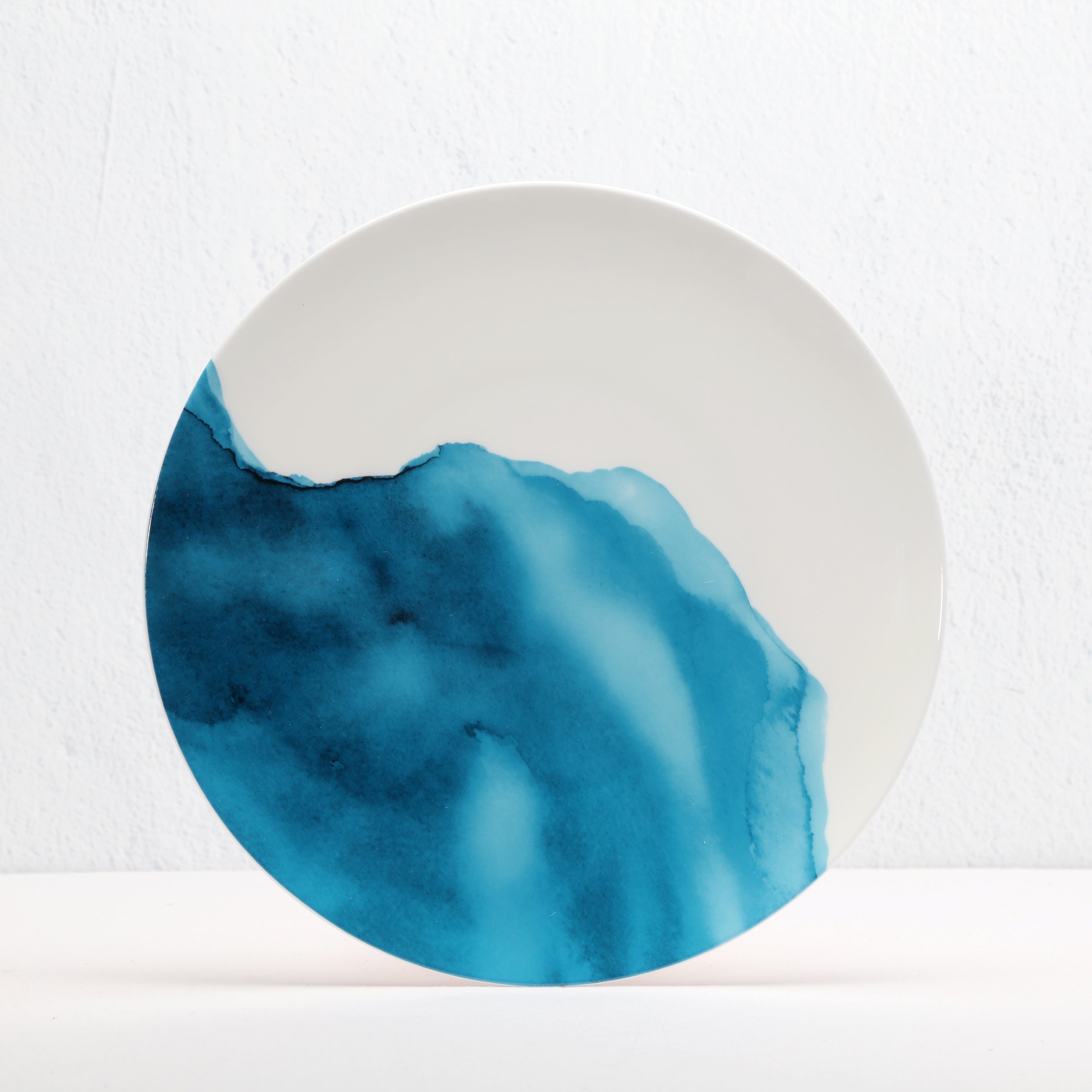 Round bone china ceramic plate with blue and white design on a white background