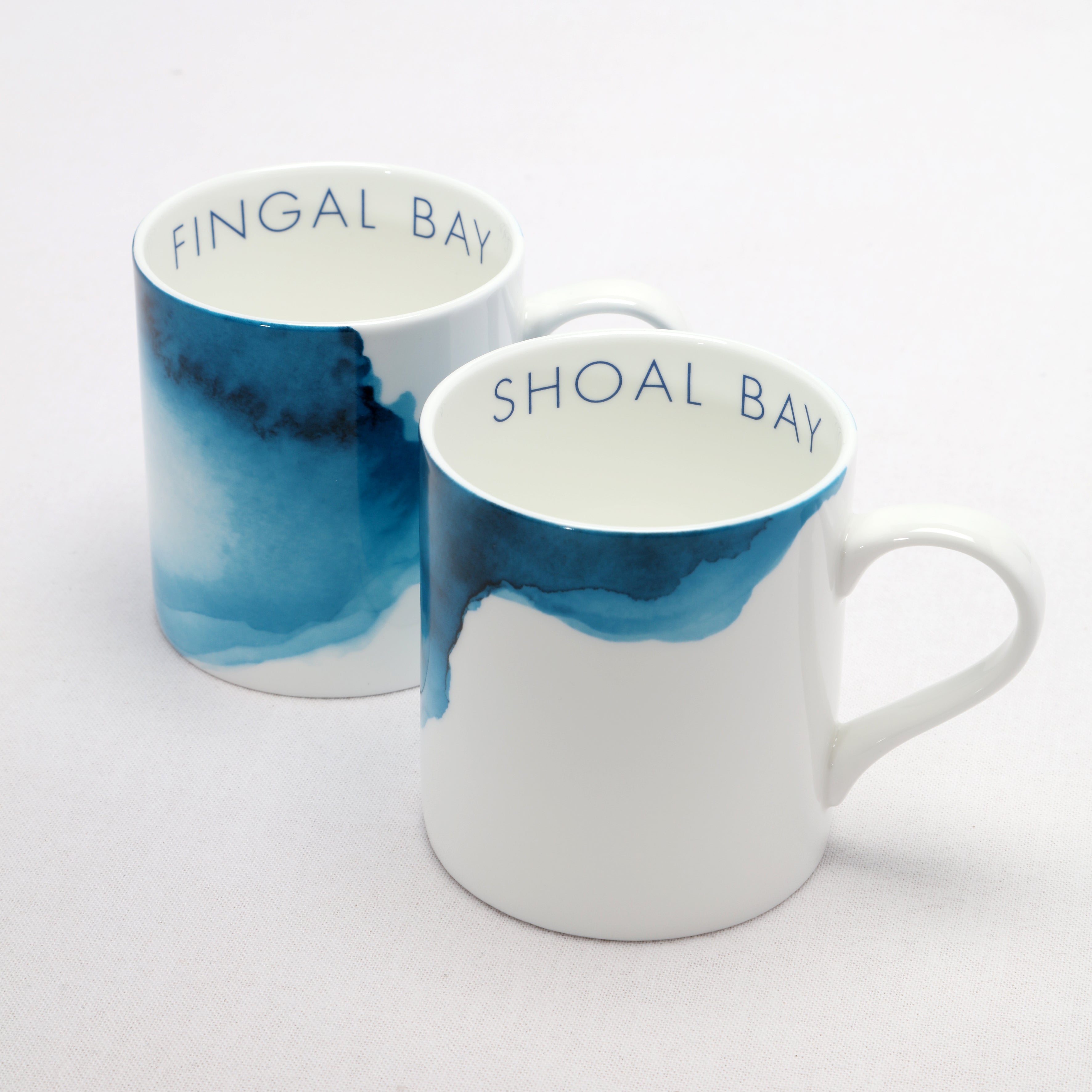 Two bone china mugs with blue and white watercolour design and text on a light gray background