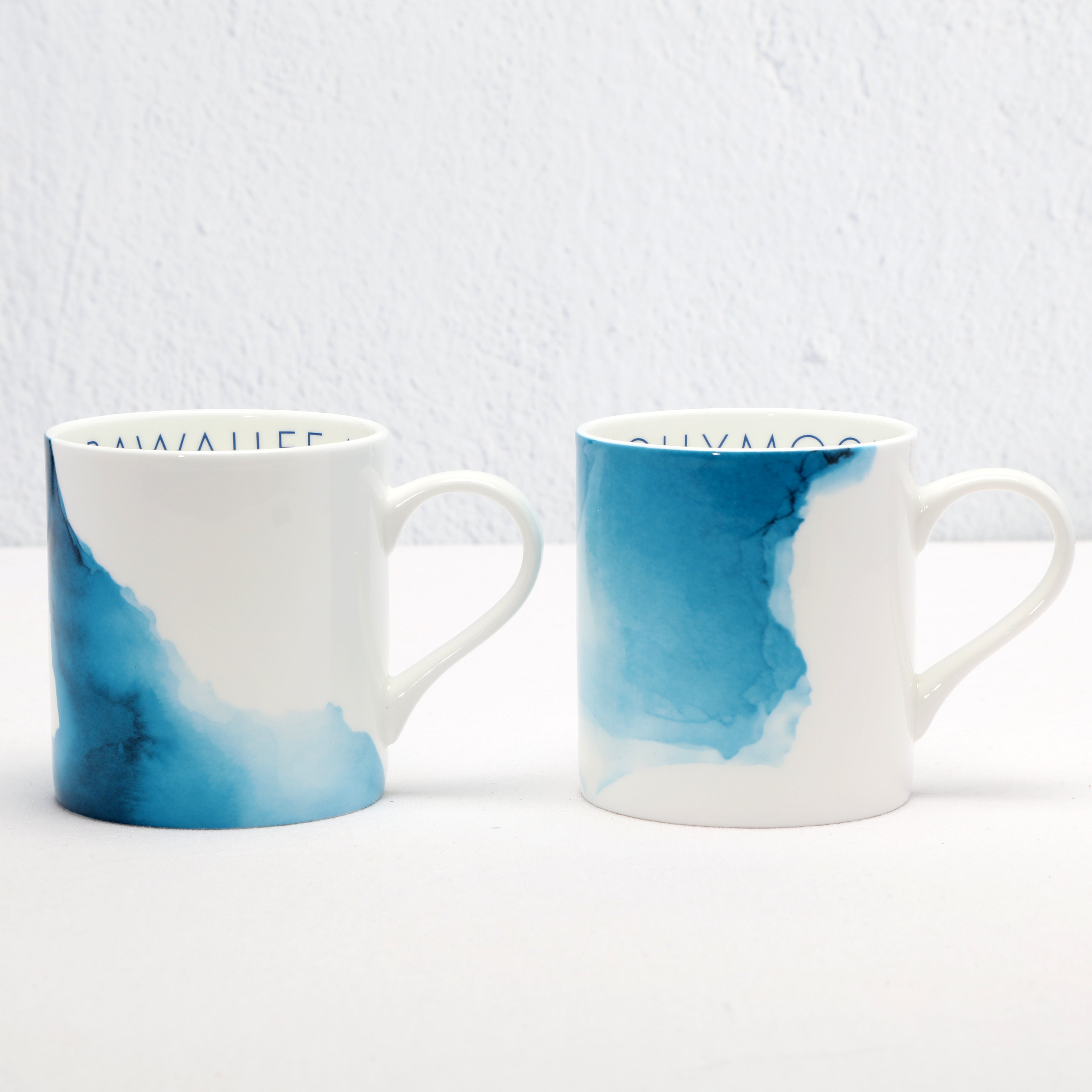 Two bone china mugs with blue water colour design on a white background