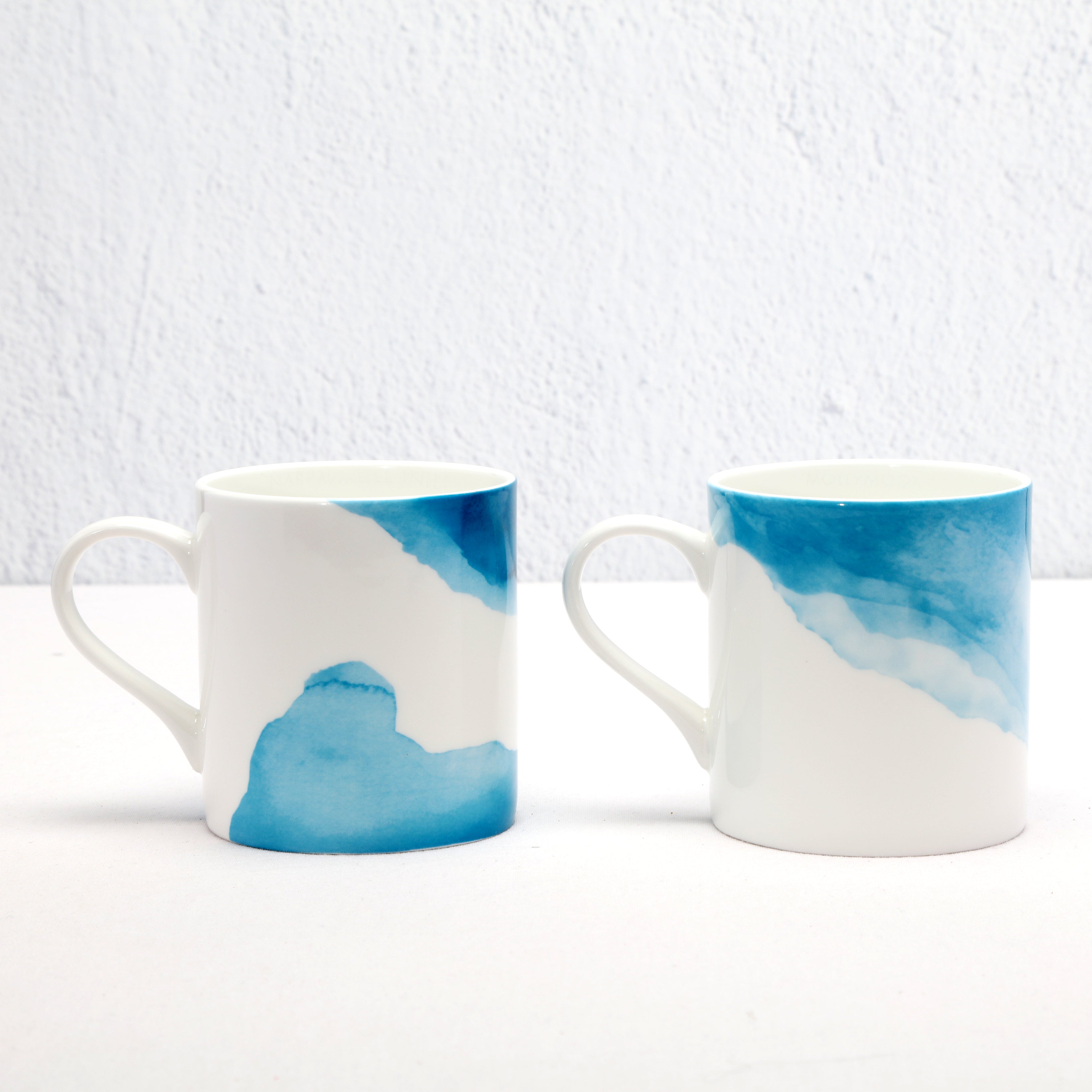 Two Bone China mugs with blue and white watercolour designs on a light gray background