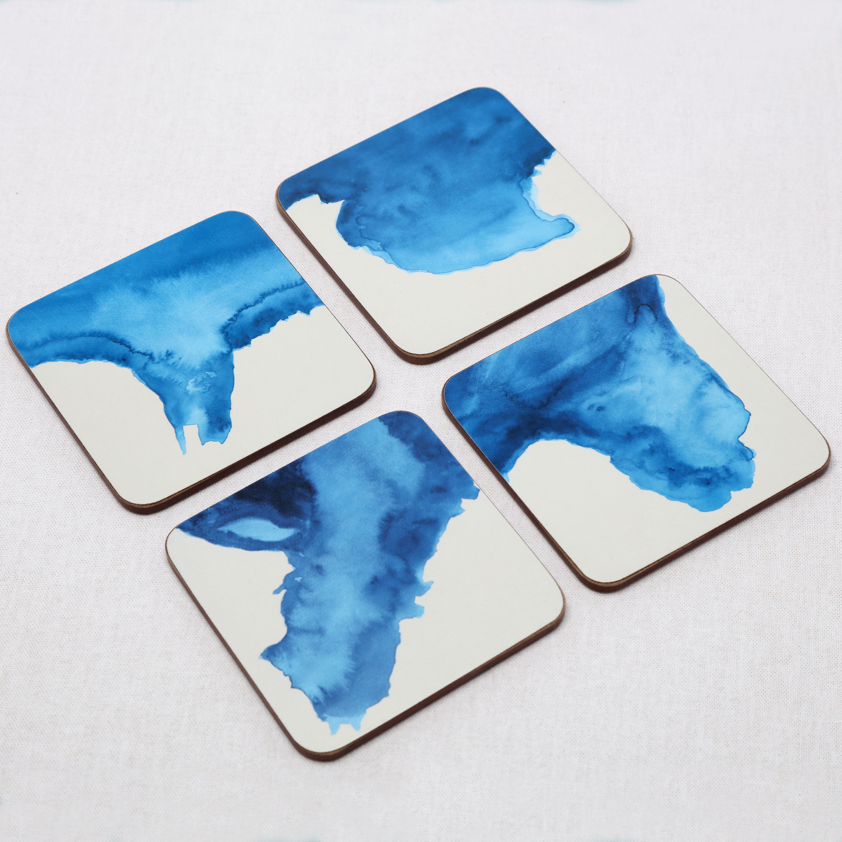 Four coasters with blue watercolor designs on a white background