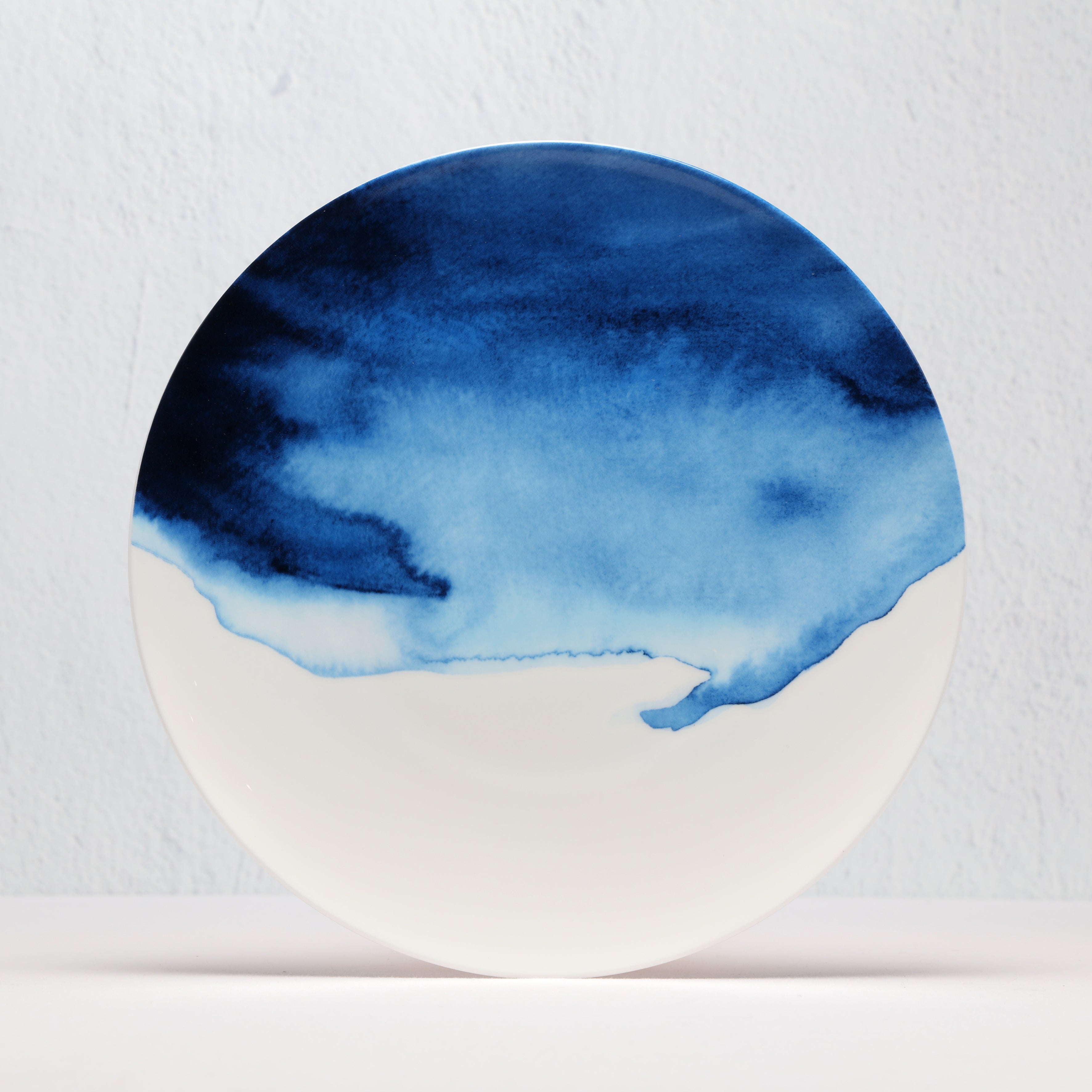 Round ceramic bone china plate with blue watercolor design on a white background