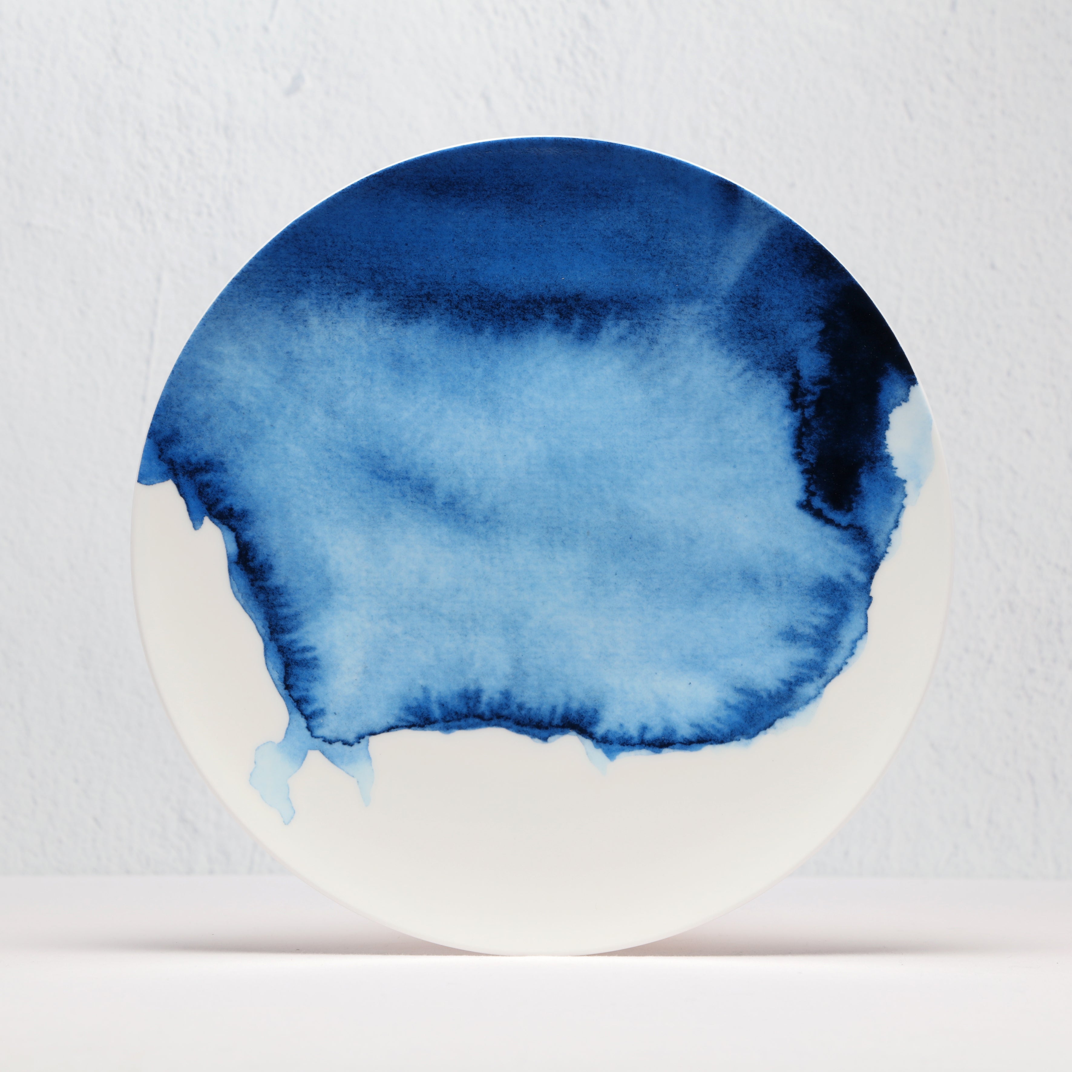 Ceramic plate with blue watercolor design on a light gray background