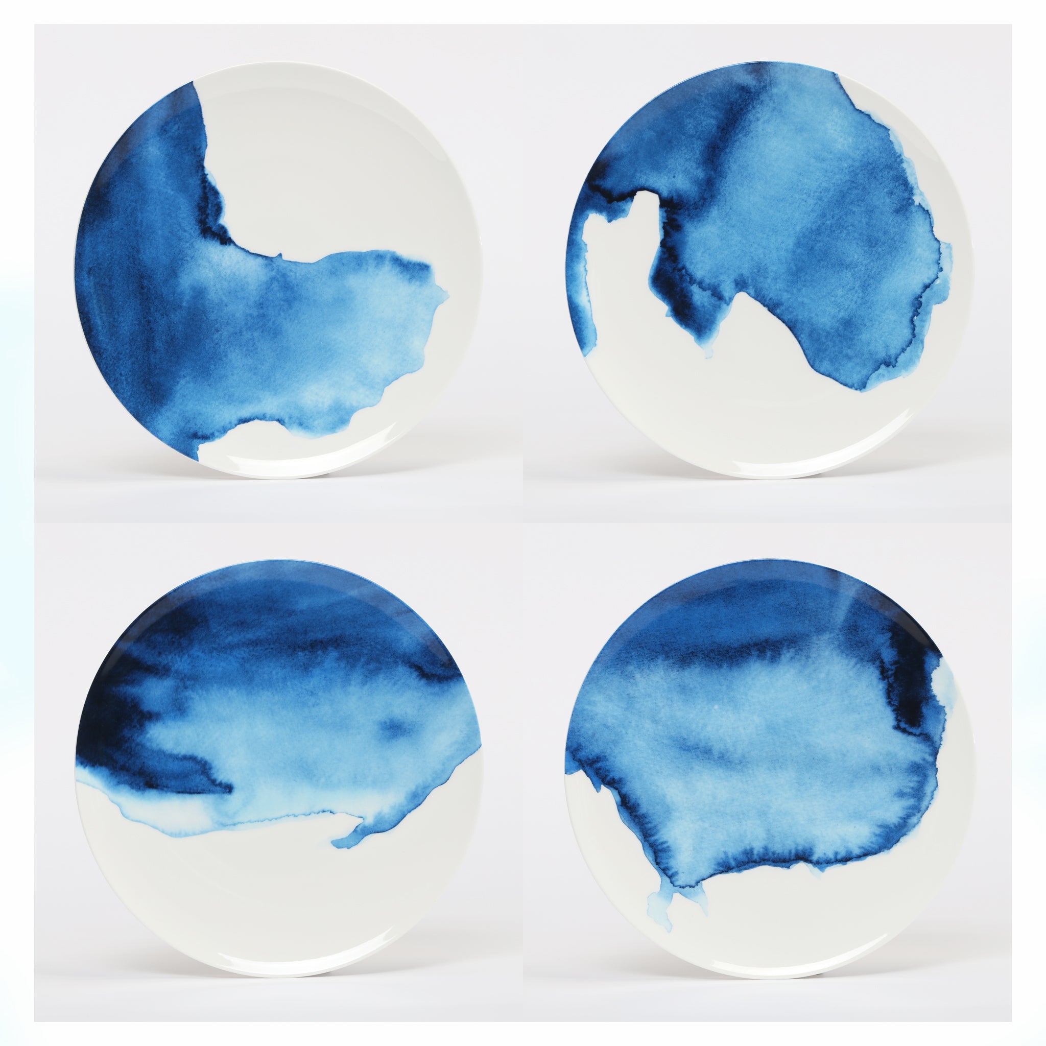 A set of four bone china dinner plates with watercolor blue illustrations of the Cornish Coastline on each.