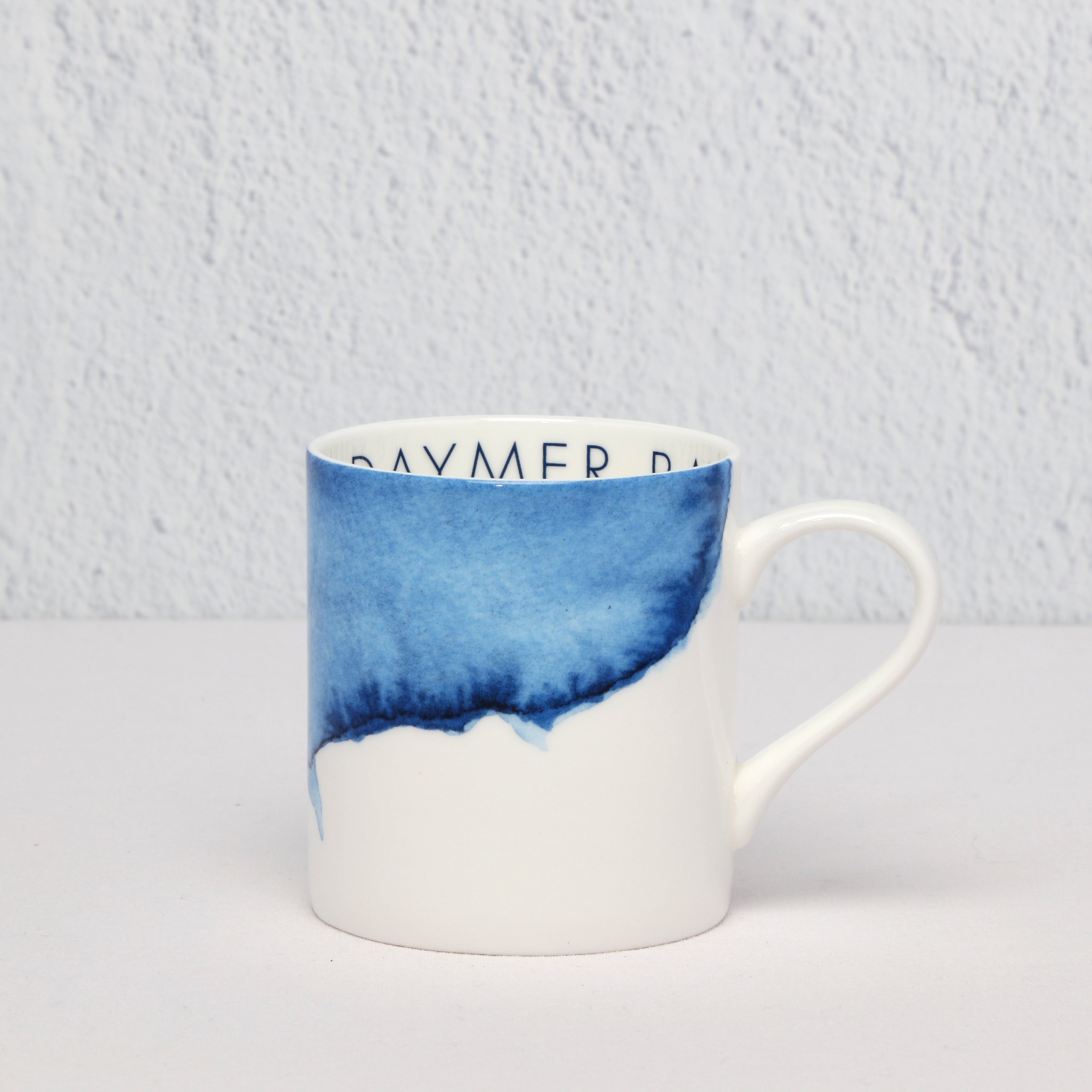 White bone china mug with blue gradient design on a light gray background