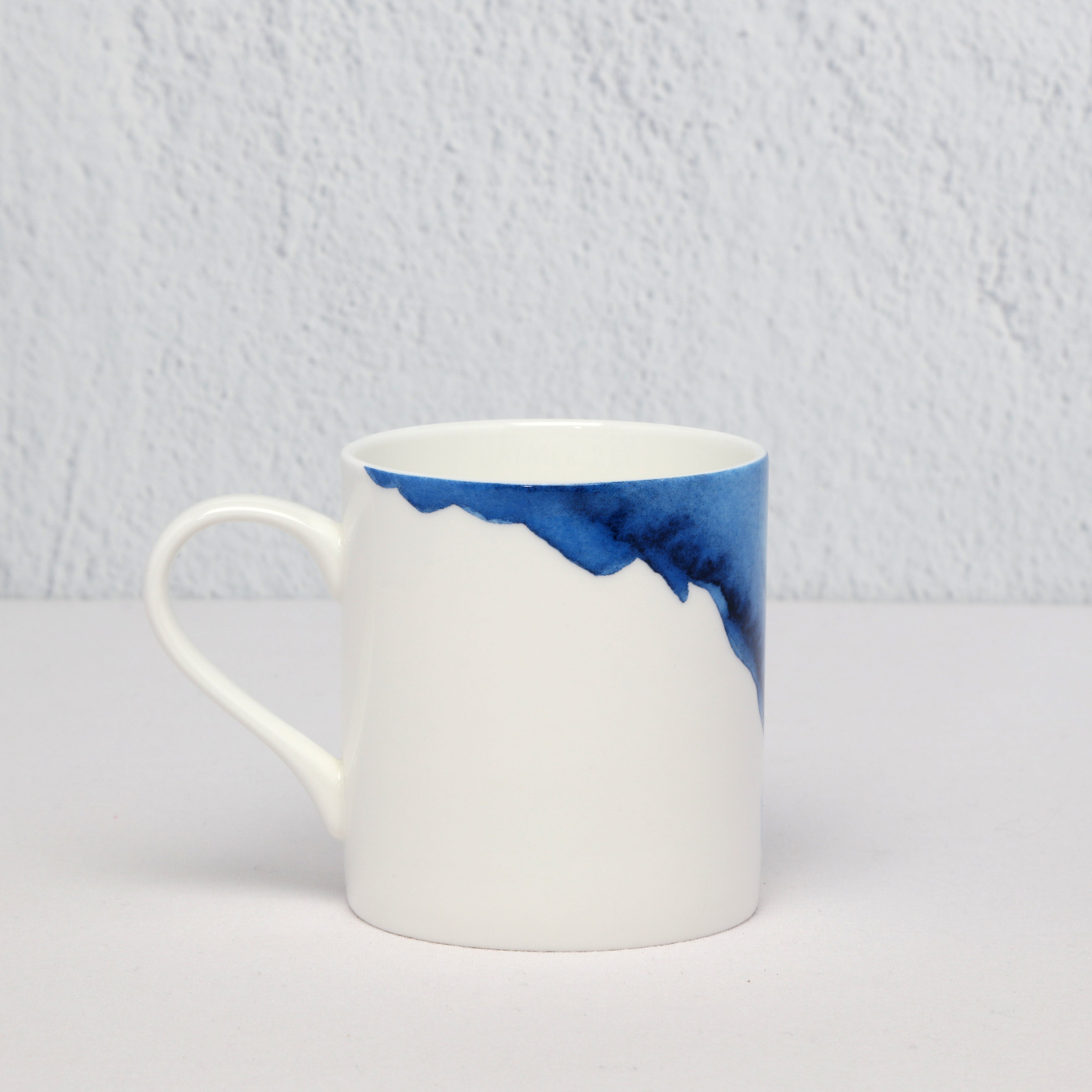 White mug with blue watercolour on a light gray background