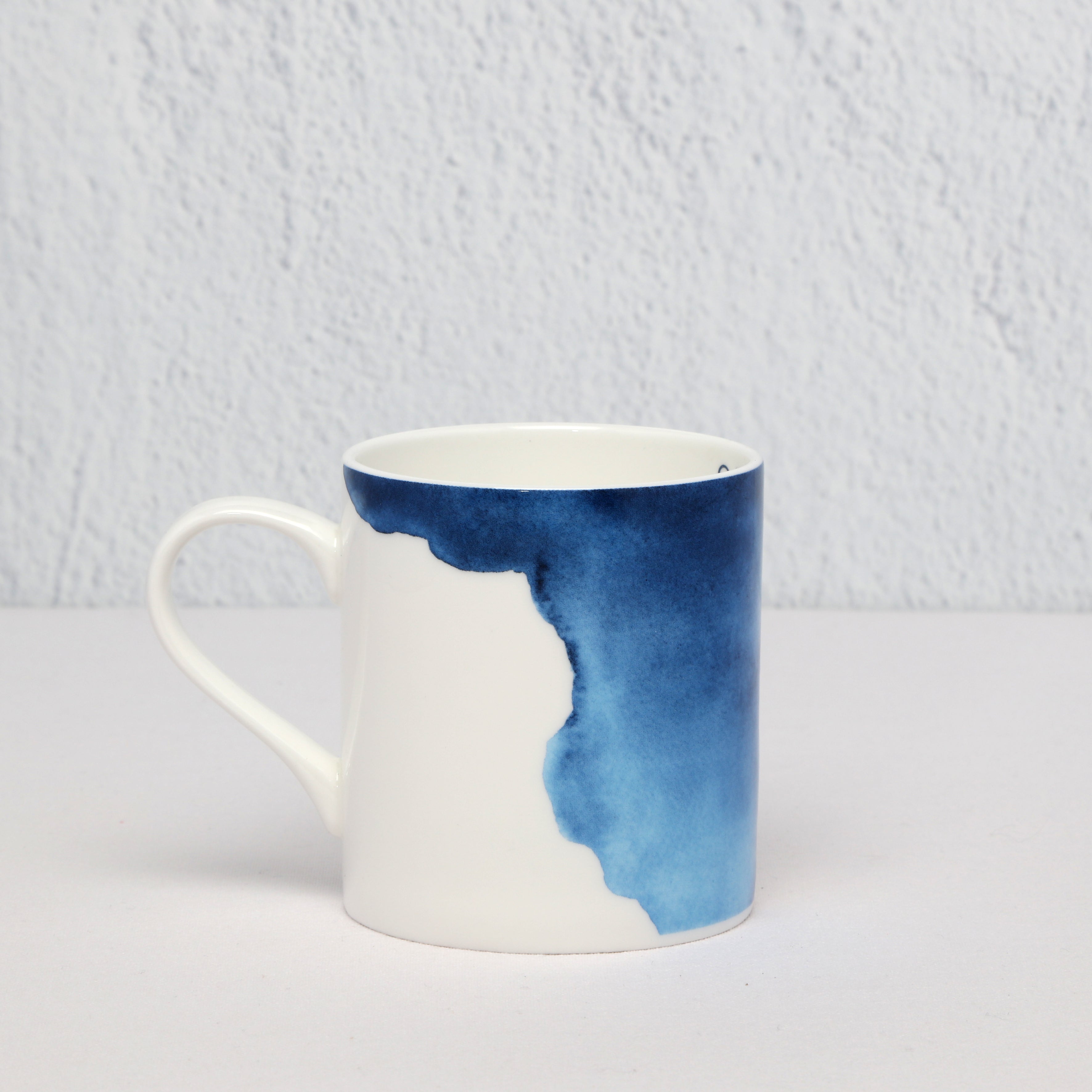 White mug with blue watercolor design on a light gray background