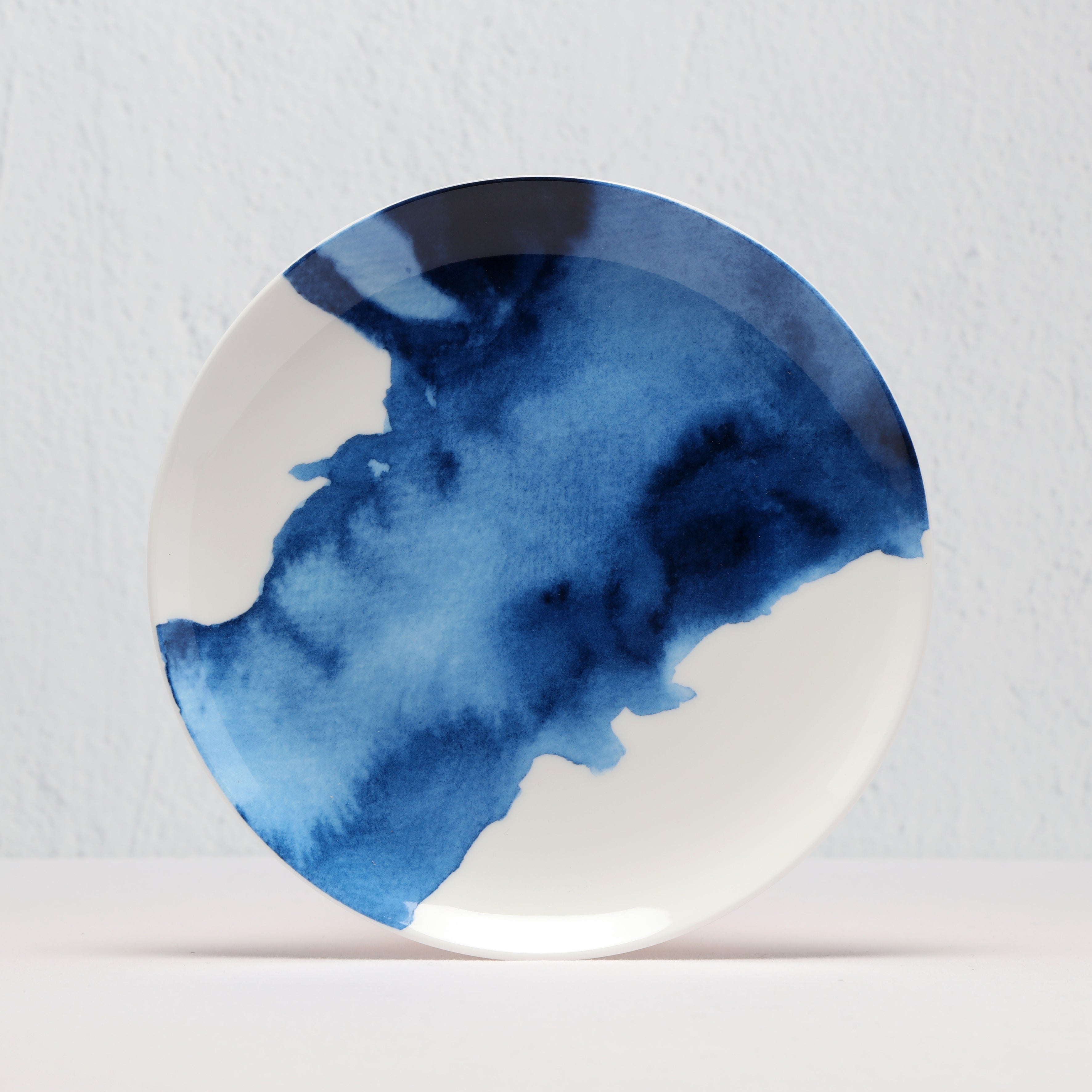 Round ceramic plate with blue watercolour design on a white background