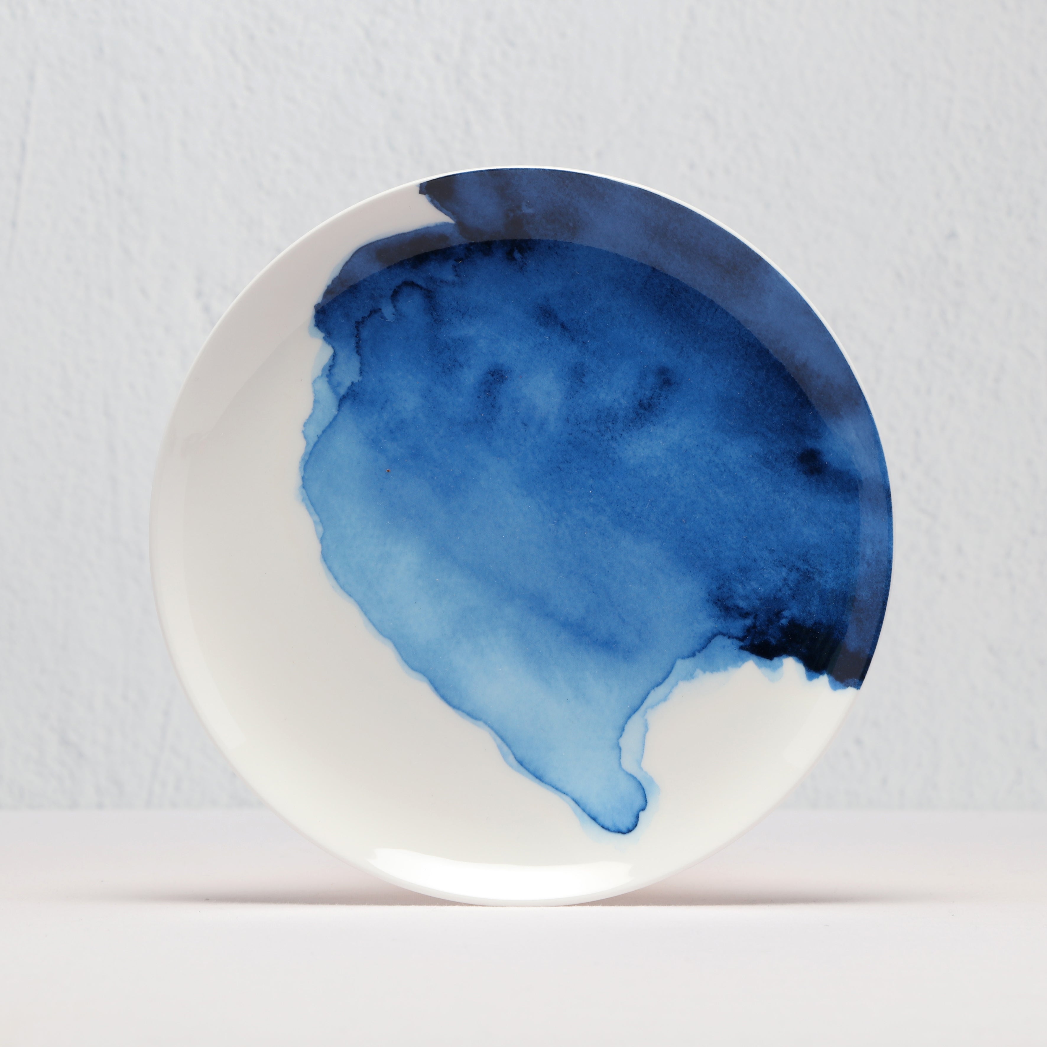 White supper bowl with a blue watercolor design on a light gray background
