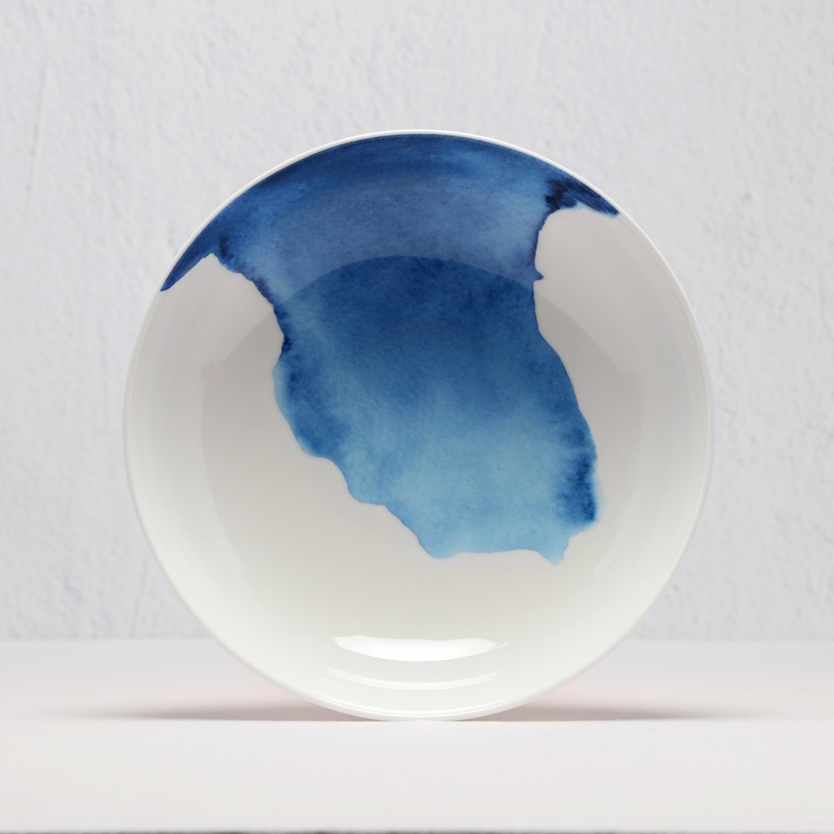 White supper bowl with blue watercolor design on a light gray background