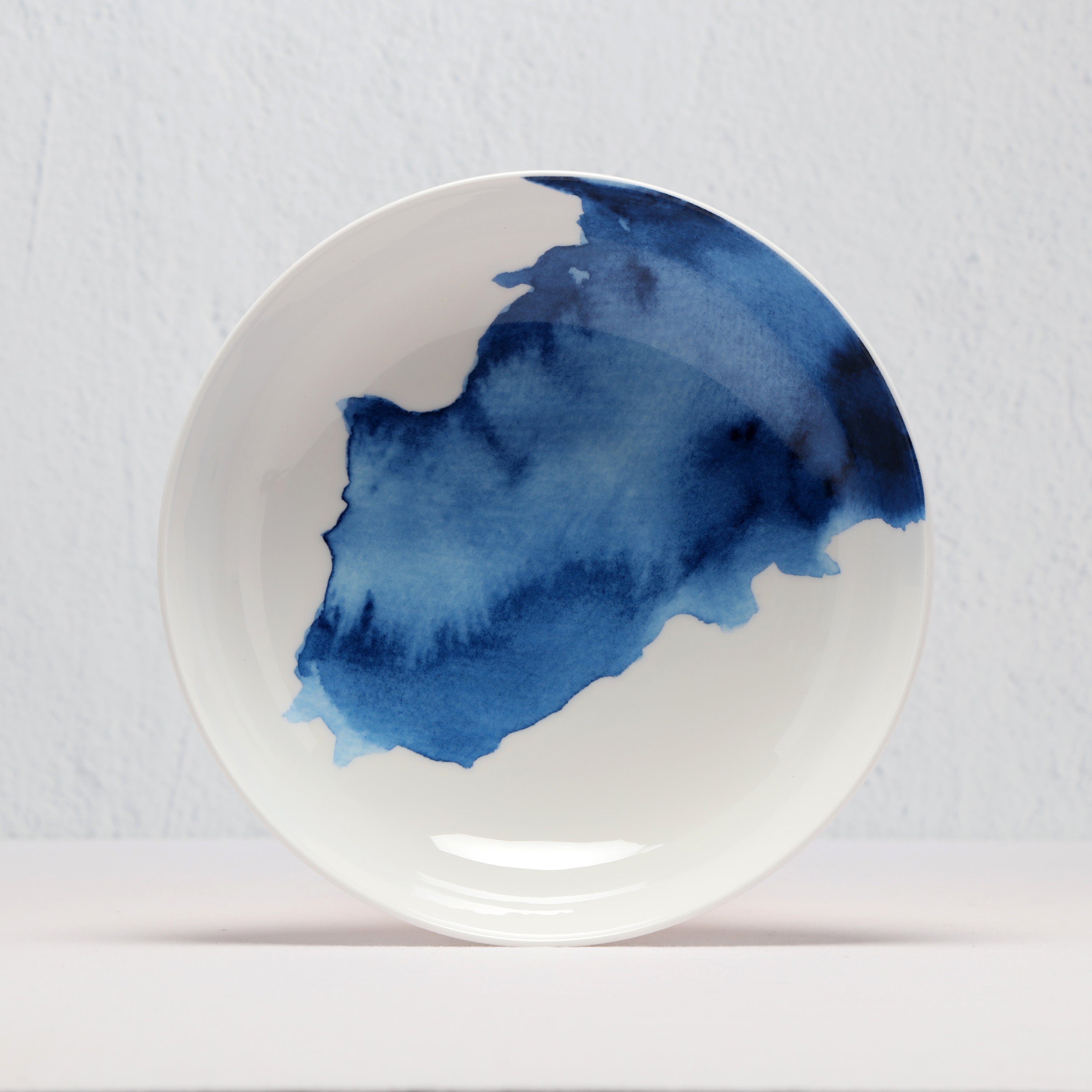 White supper bowl with blue watercolor design on a light gray background