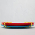 Stack of colorful melamine plates on a light gray background side view