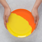 Colorful melamine plate held by hands on a light gray background
