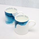 Two mugs with blue watercolor design and text on a white surface at angle 