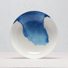 White supper bowl with blue watercolor design on a light gray background